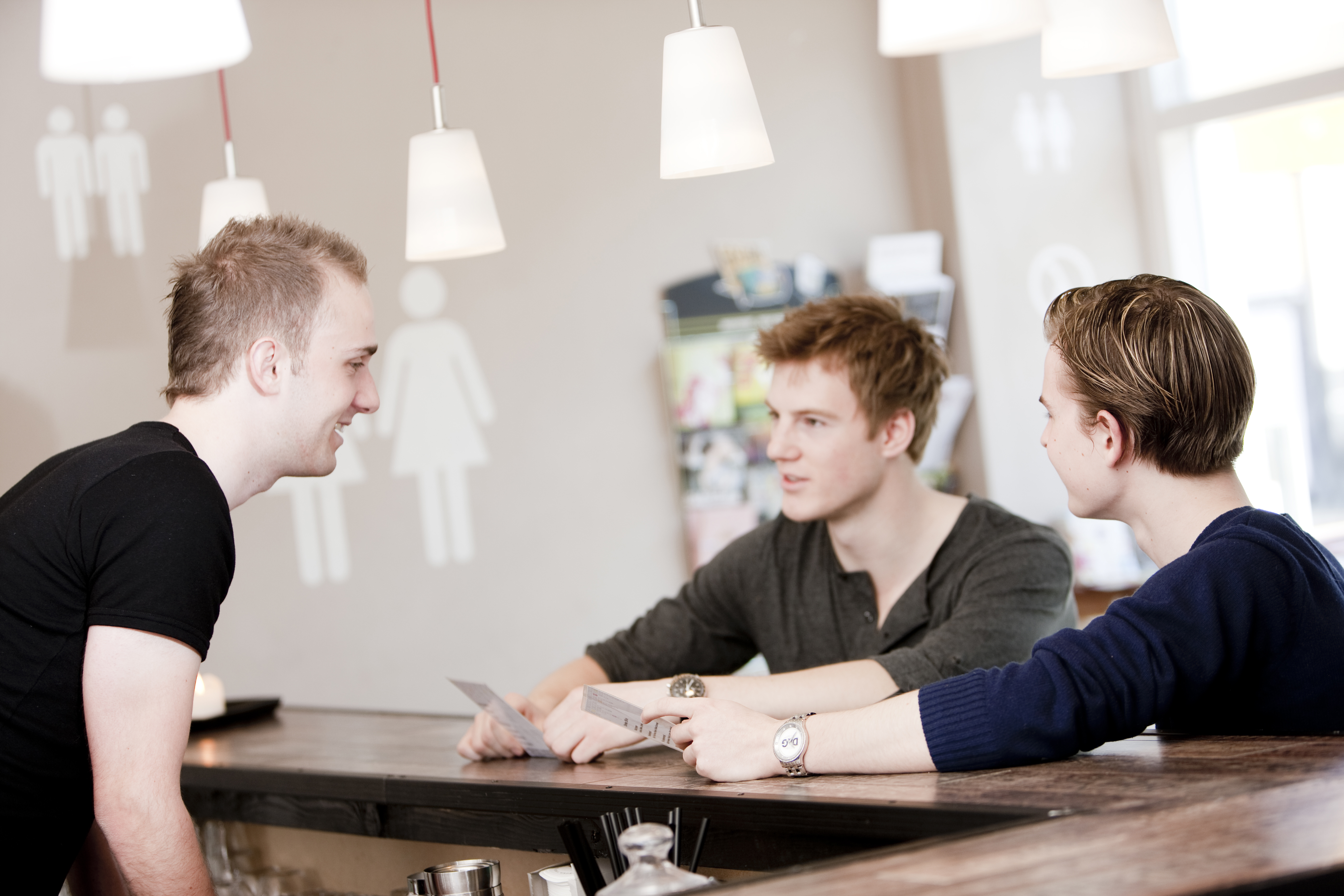 Tre unge mænd sidder om et borg