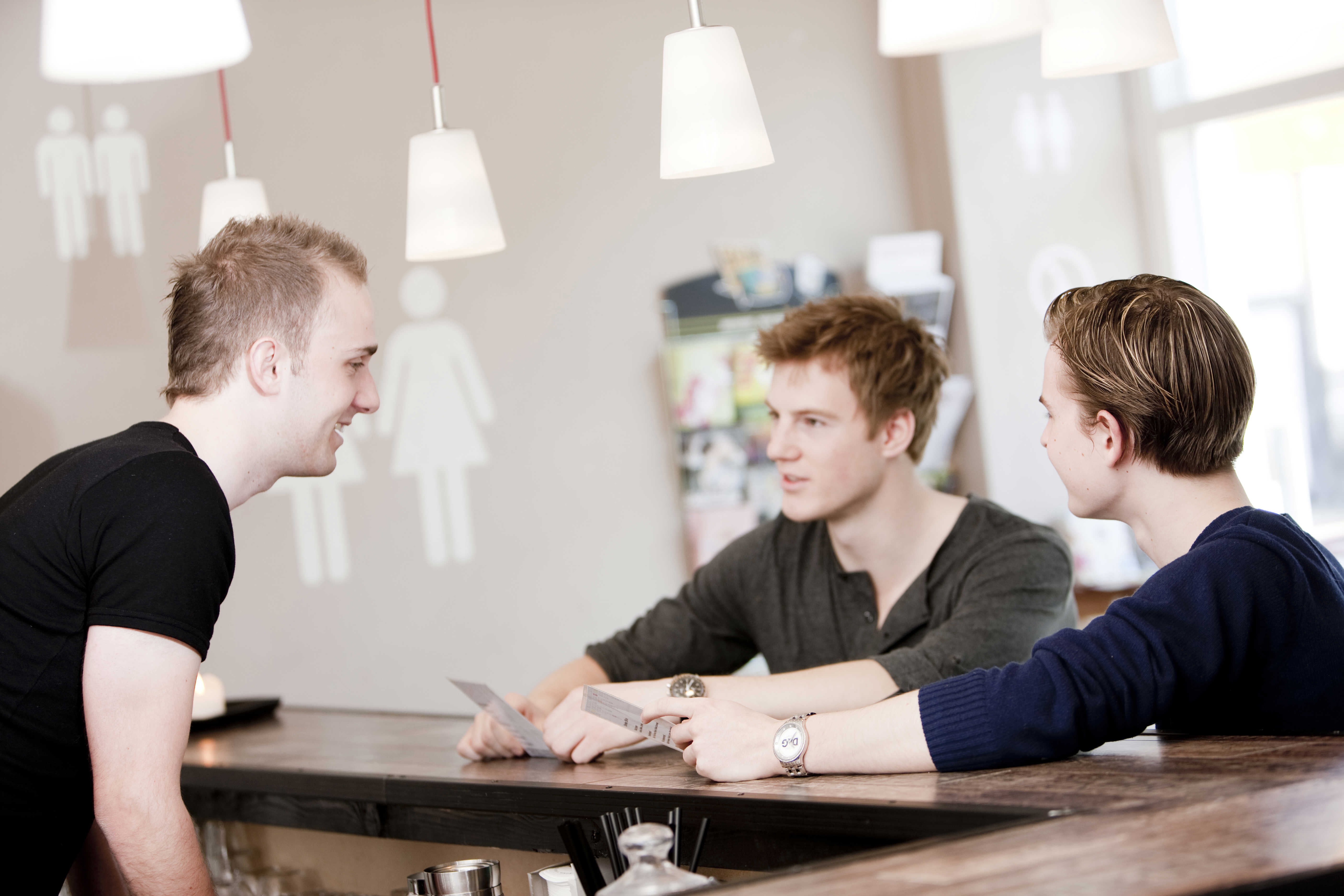 Tre unge mænd sidder om et borg