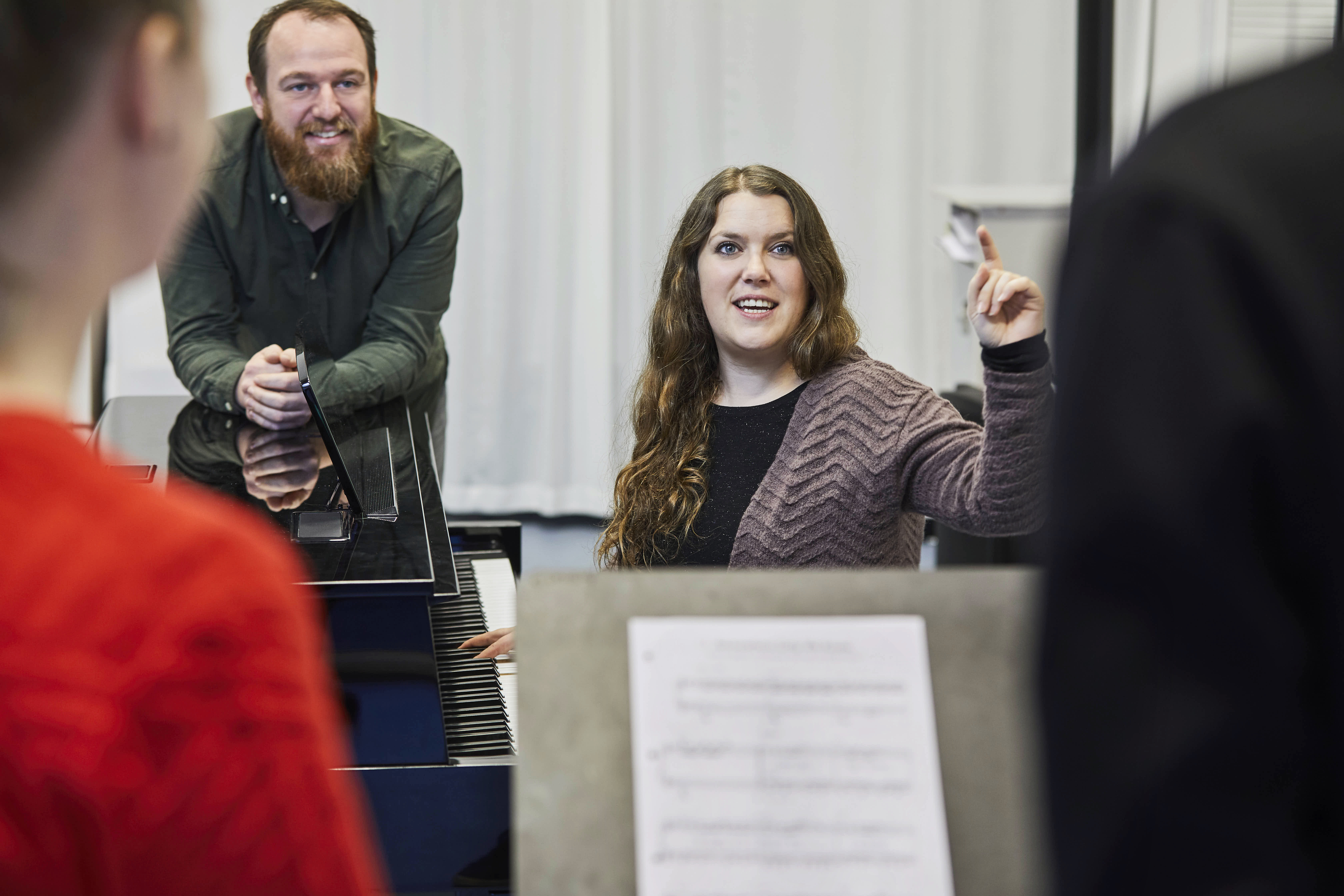 Kvinde dirigerer kor fra klaver