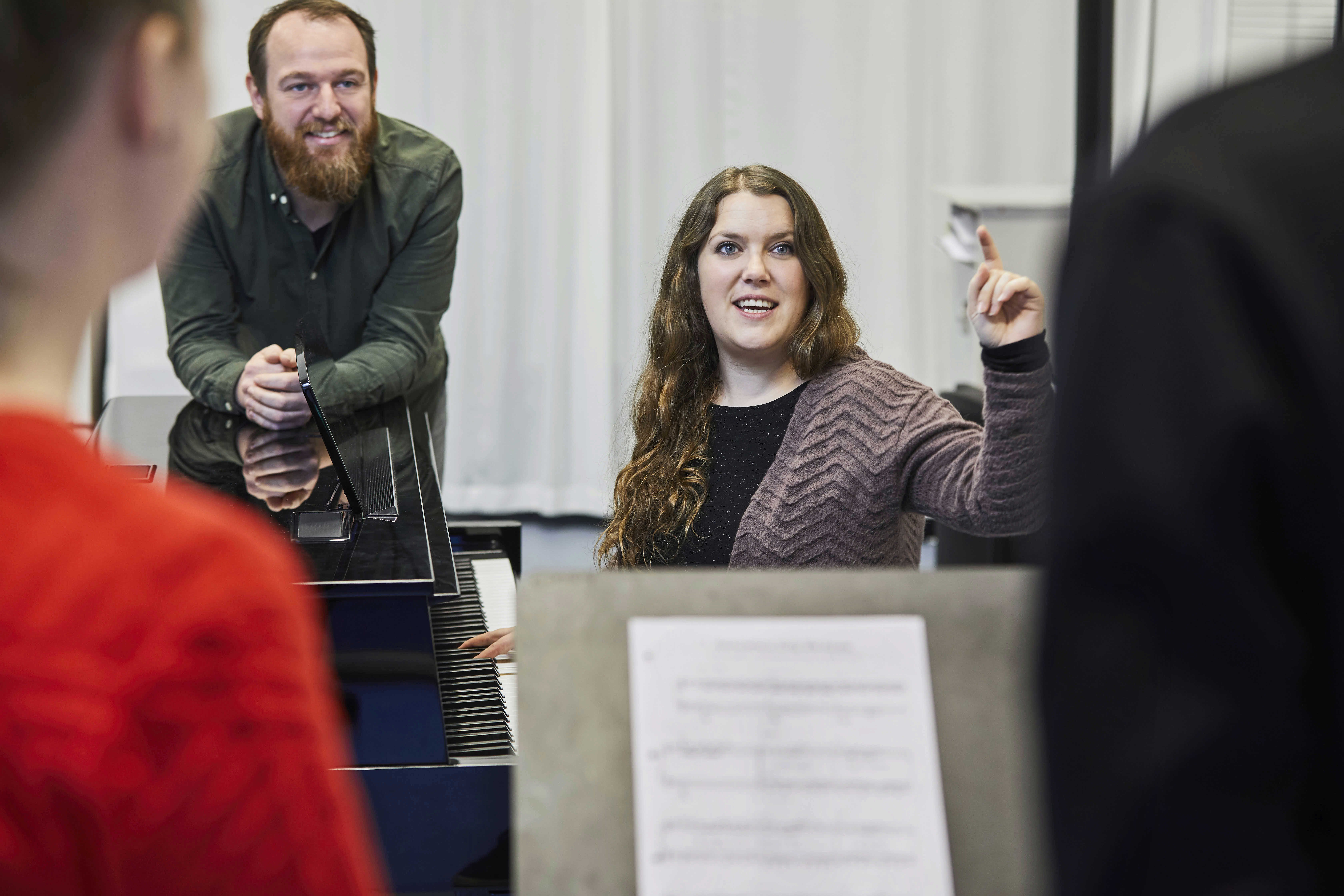 Kvinde dirigerer kor fra klaver