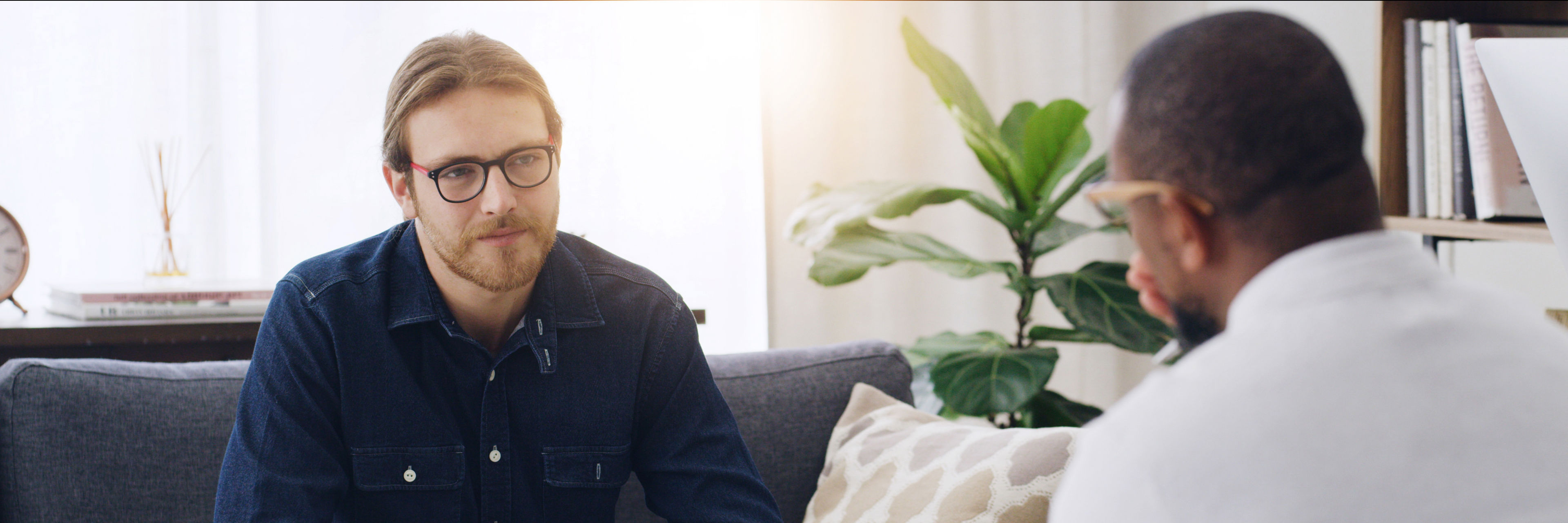 Mand sidder i sofa og taler med mand overfor