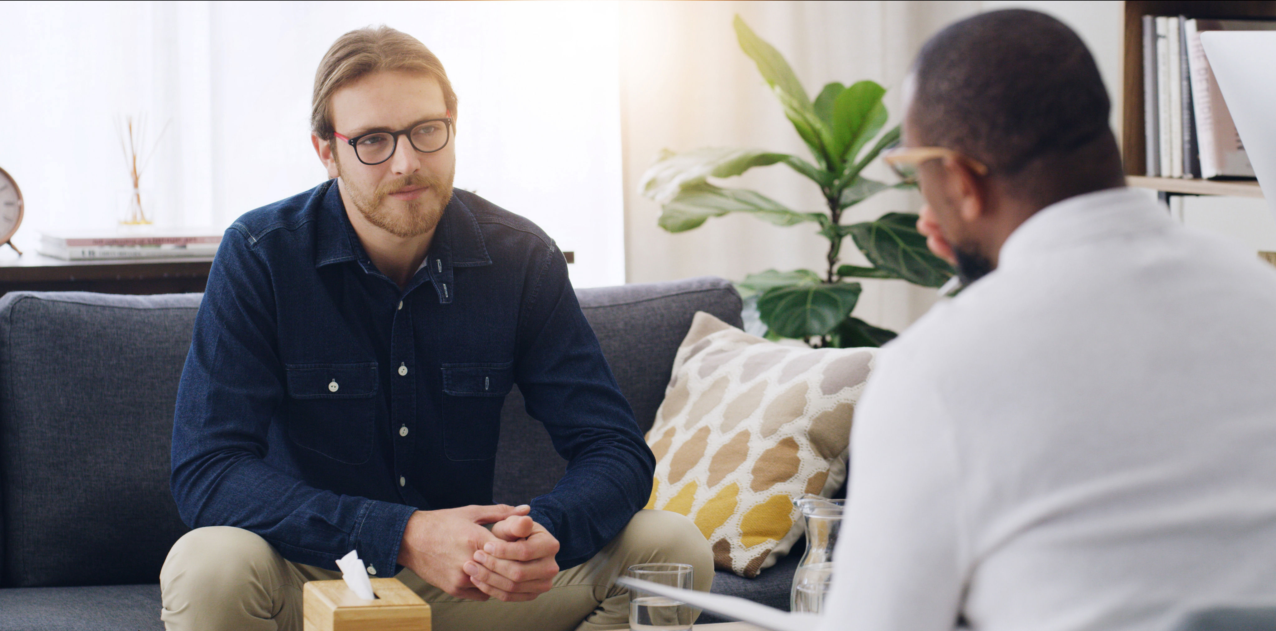 Mand sidder i sofa og taler med mand overfor