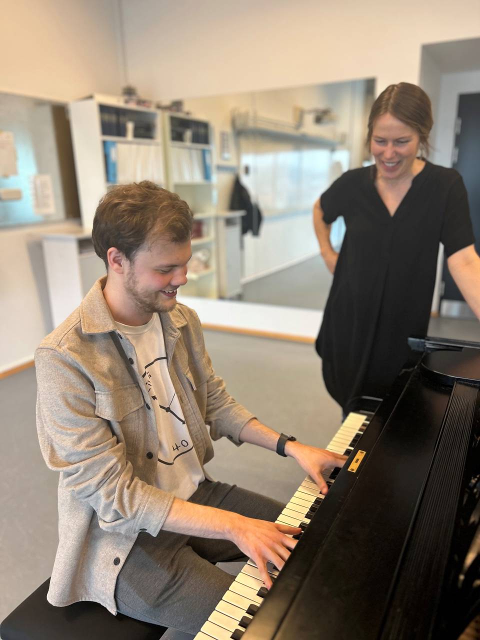 Mand spiller klaver mens kvinder kigger på