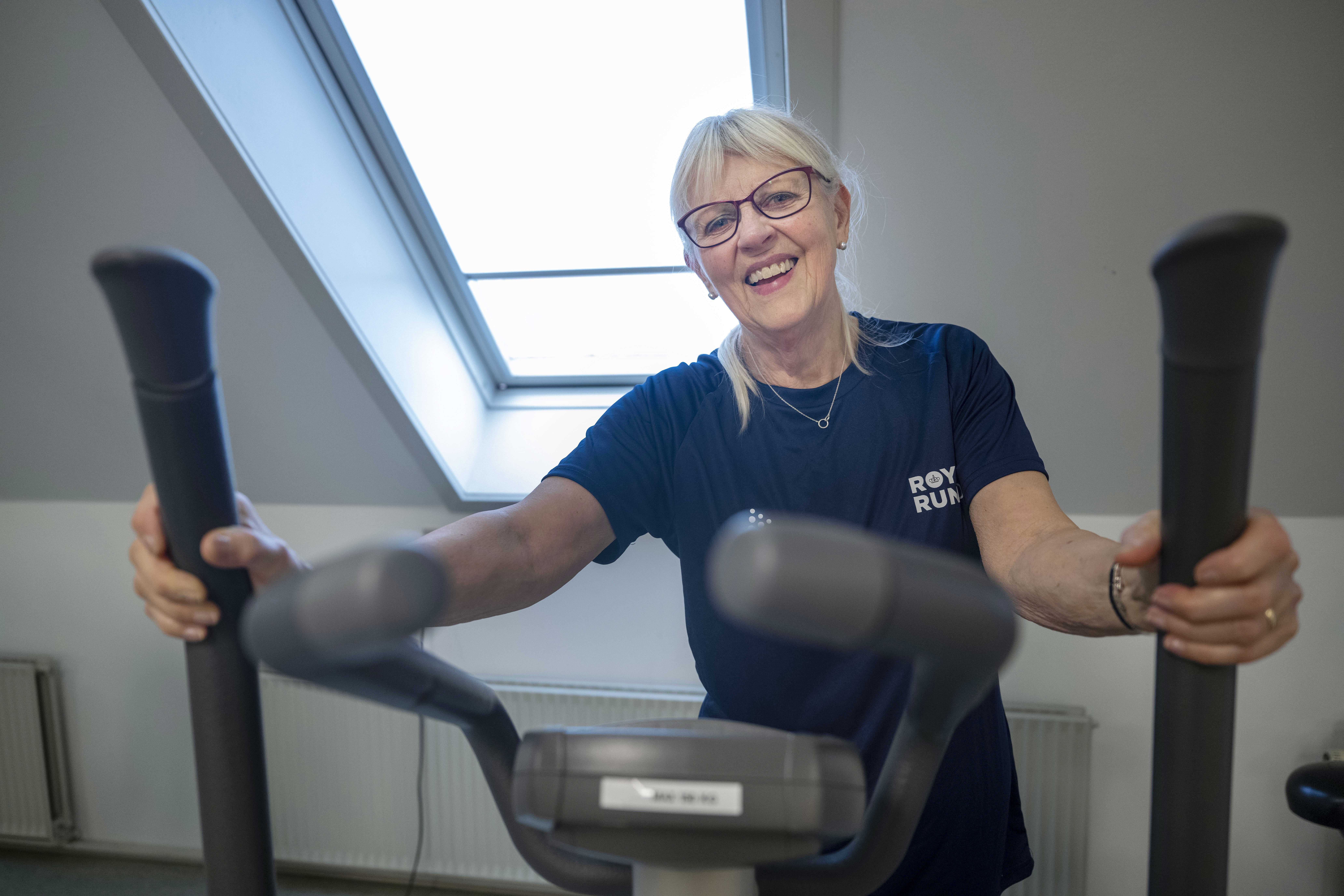Smilende kvinde på crosstrainer