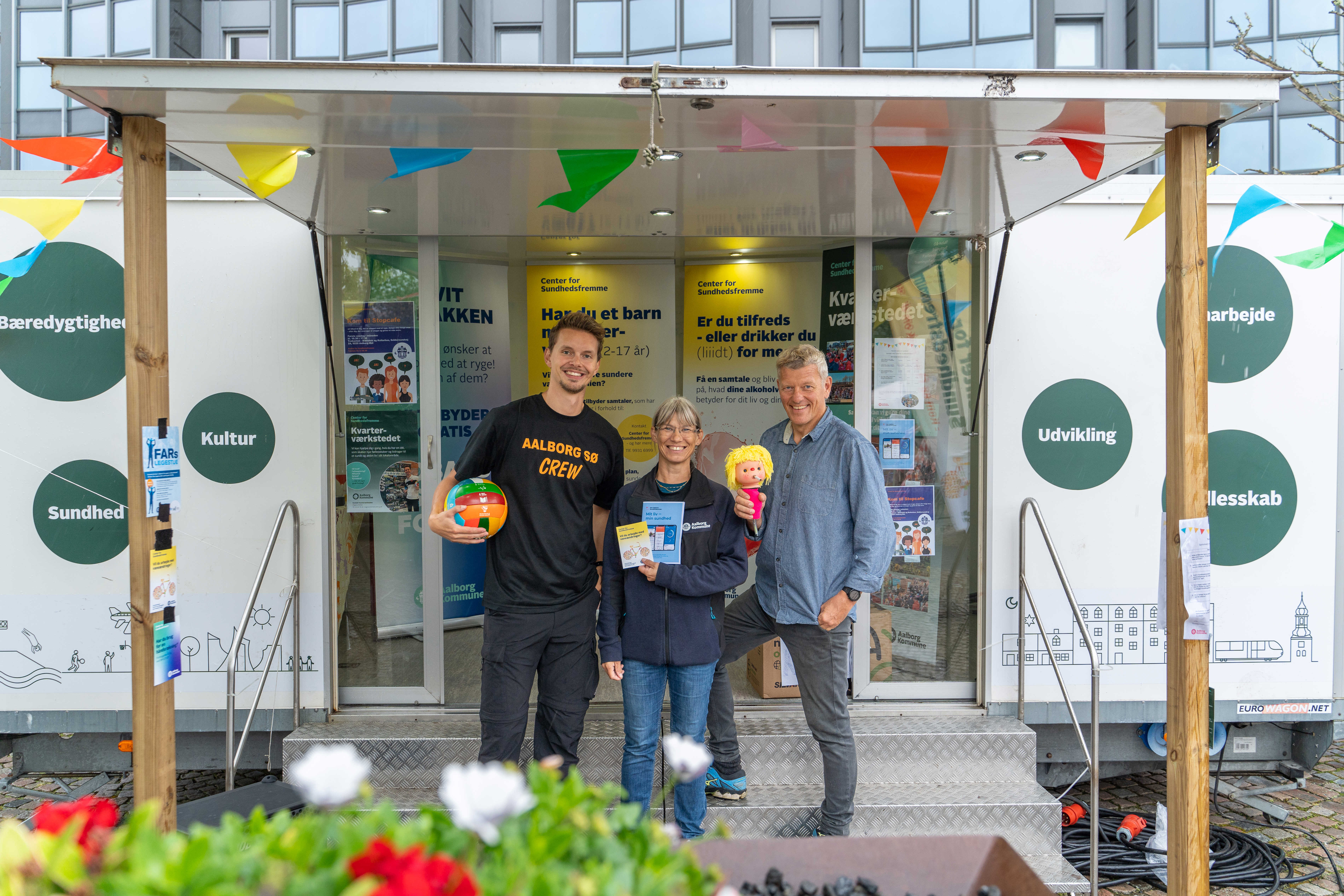 Tre menneske foran en pavillionvogn