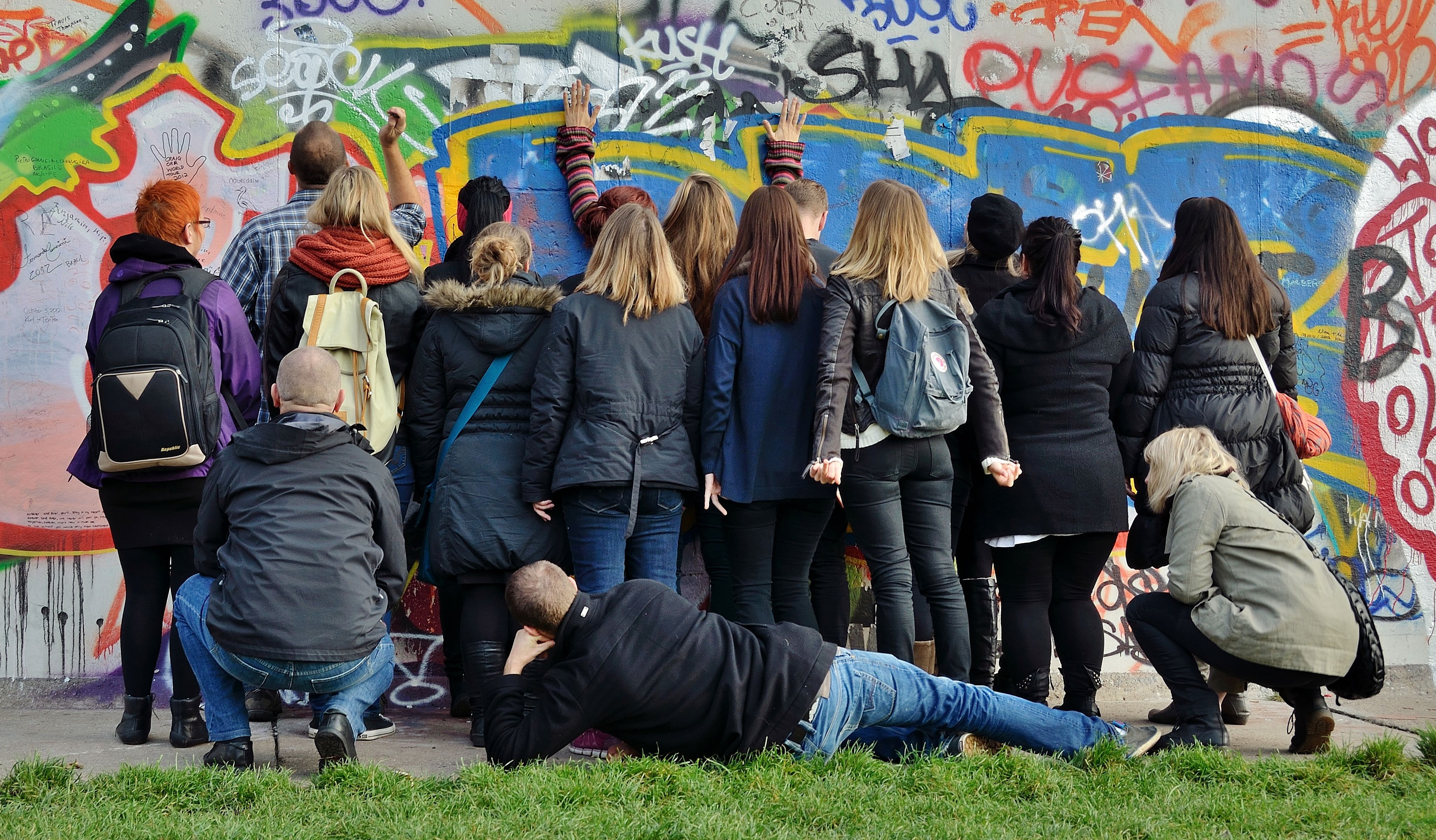 Gruppe af unge står med ansigterne mod mur og betragter graffitti