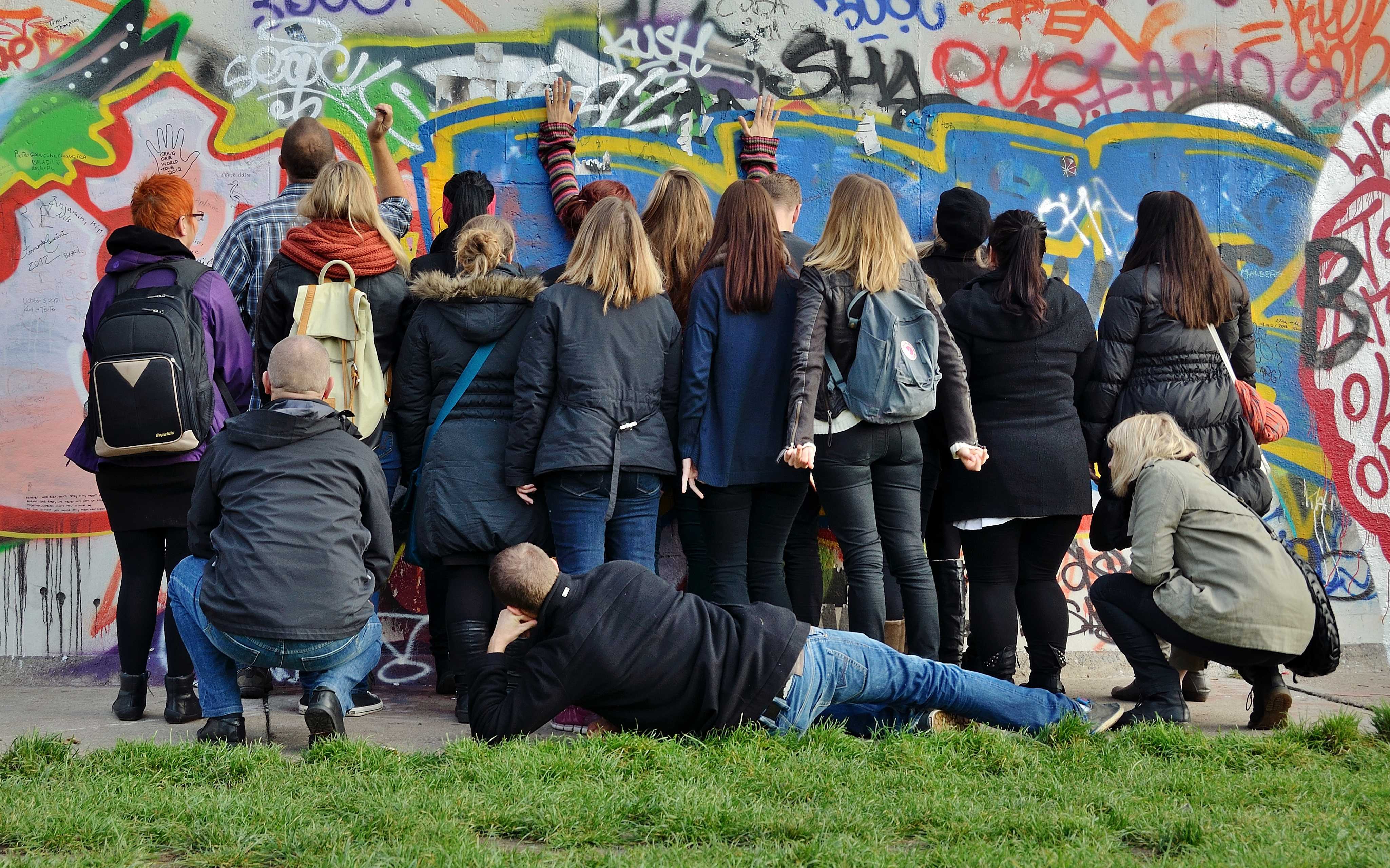 Gruppe af unge står med ansigterne mod mur og betragter graffitti