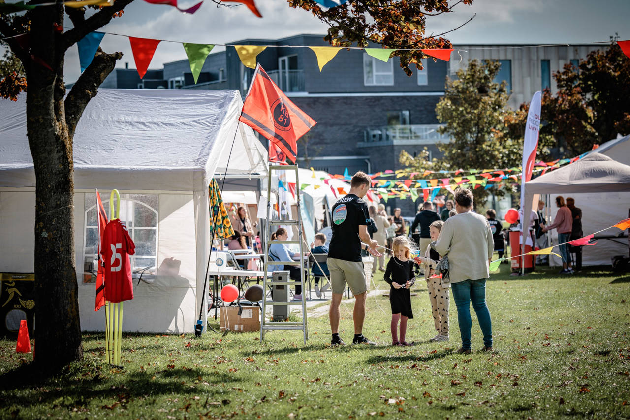 Telte og mennesker til byfest på græs.