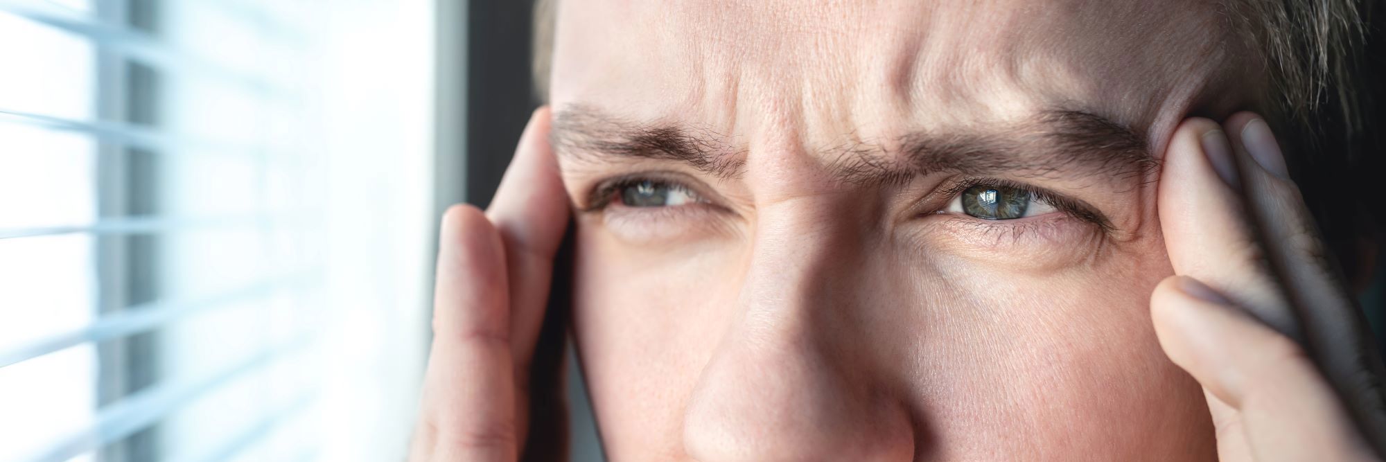 Mand der holder begge hænder op til tindingen