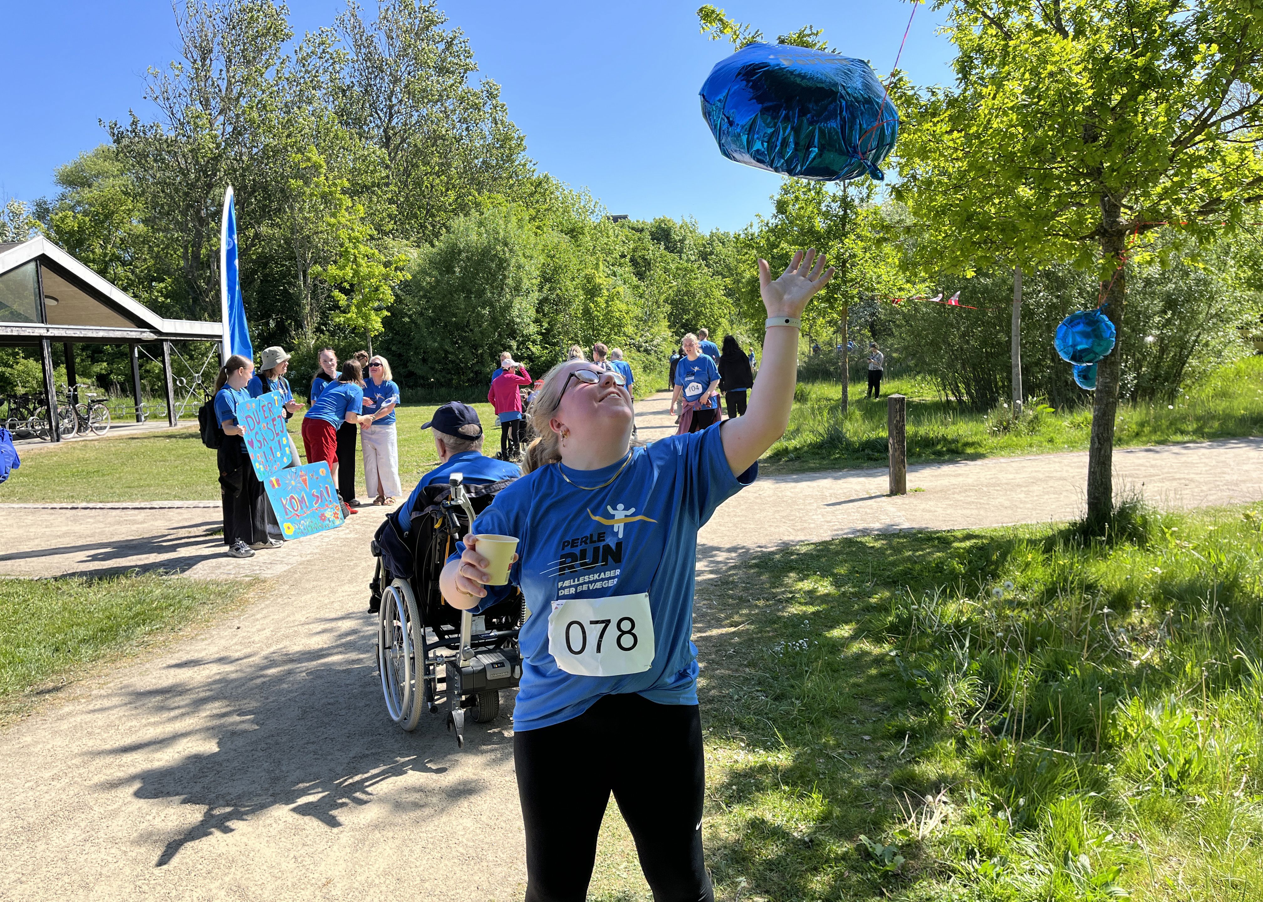 Silje står med en perlerun t-shirt og slår til en blå flot ballon